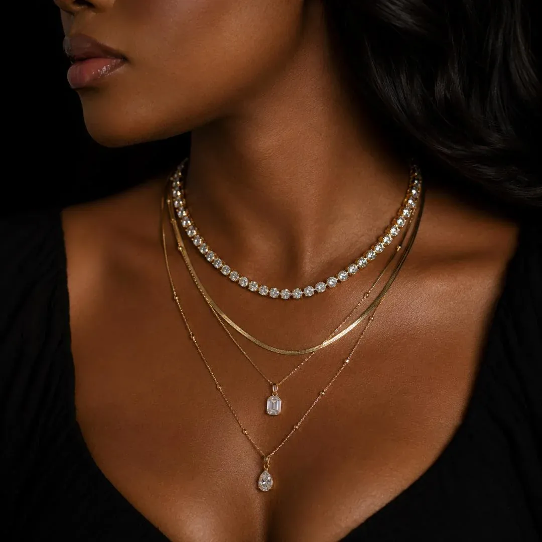 Model wearing layered Saint Collection gold necklaces with crystal pendants