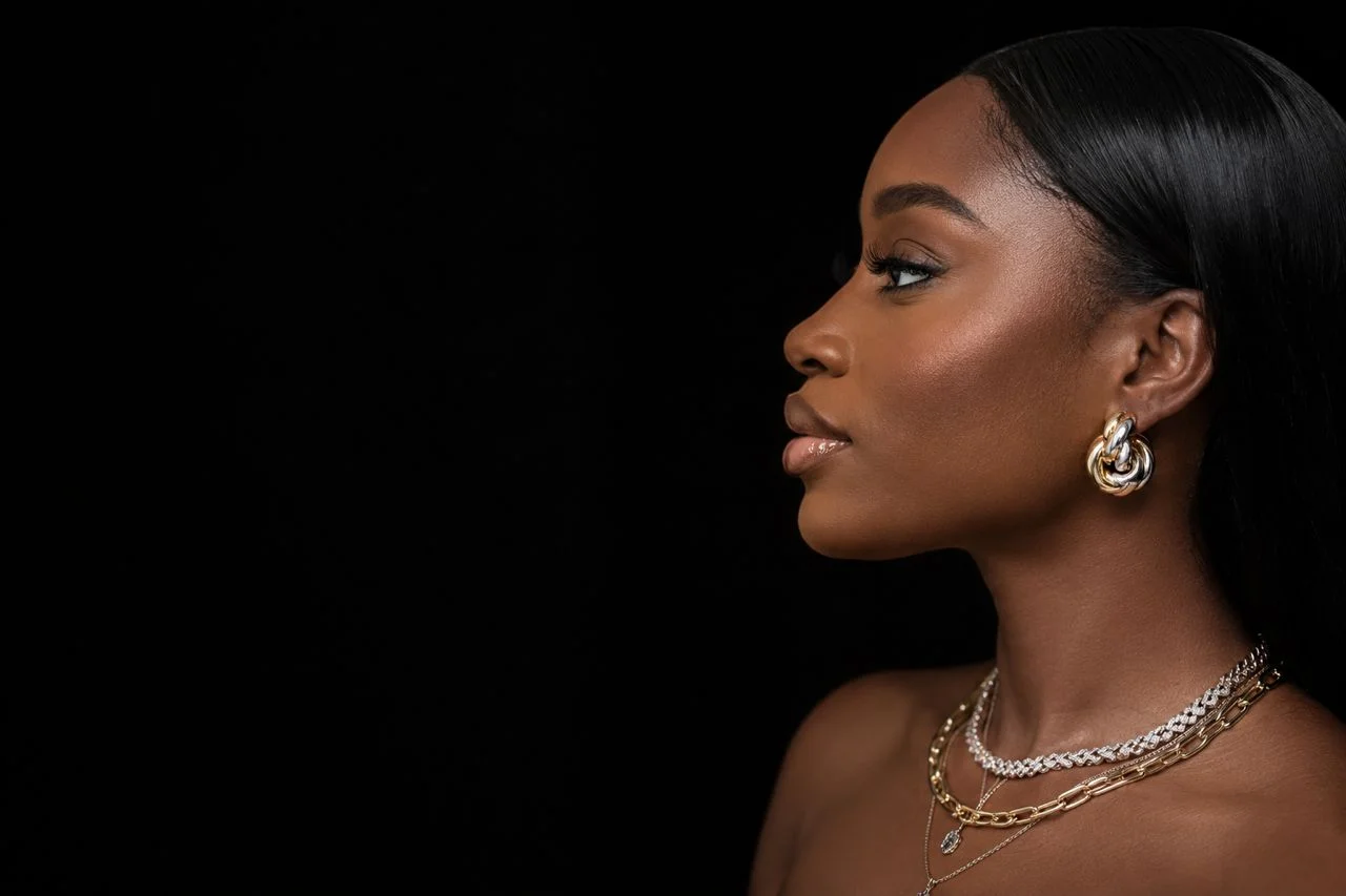 Model in profile wearing Saint Collection gold earrings and layered necklaces